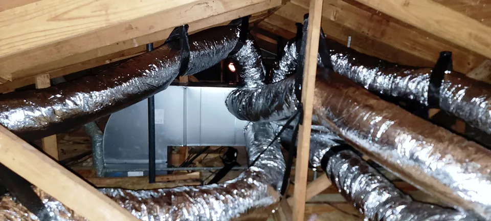 Insulated ducts connect to a metal air-distribution box in a framed attic