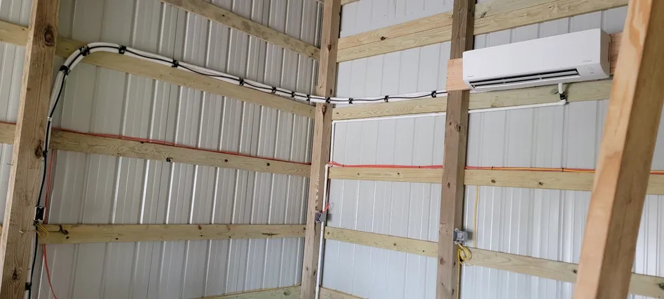 Wall-mounted ductless indoor unit and routed lines inside a framed metal building