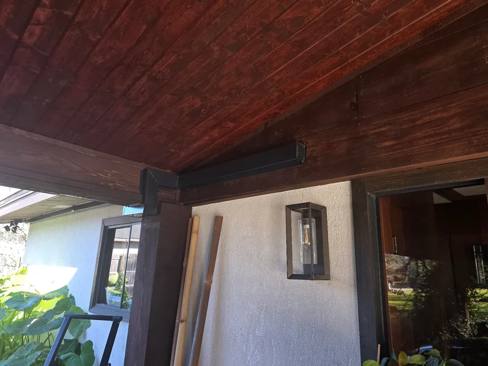 Dark fitted line cover follows a wooden porch beam and post